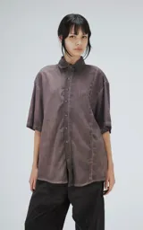 Camisa manga corta color gris con efecto desgastado, corte holgado y cierre frontal con botones.