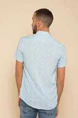 Camisa celeste con estampado floral blanco, de manga corta y corte clásico. Cierre frontal con botones.