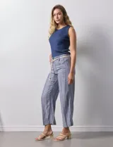 Pantalón de lino a rayas verticales azules y blancas, con corte ancho, pretina con pasadores, cierre y botones. Incluye cinto de soga con nudo.