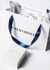 Dije de acero quirúrgico rectangular con bordes redondeados y gancho metálico. Incluye grabado personalizado de nombres en tipografía cursiva.