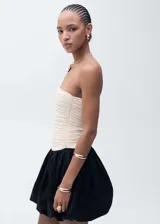 Vestido corto evasé, palabra de honor, con diseño drapeado y combinado en color crudo y negro. Falda globo con cierre de cremallera invisible lateral.