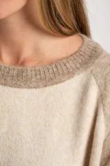 Sweater de tejido de punto con diseño color block. Cuerpo principal en beige jaspeado, mangas y puños en azul marino, y detalles en marrón en el cuello y puños.