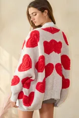 Sweater cardigan oversize color gris con estampado de corazones rojos.