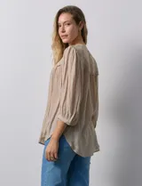 Blusa color beige de gasa, marca Figueroa & Flower. Cuello a la base, escote en V y abertura central con botones. Hombros y espalda en crochet. Manga 3/4 amplia con puño y botón.