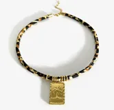 Gargantilla con cordón estampado animal print y dijes dorados con diferentes motivos: concha, sol, corazón, golondrina, pez y palmera.