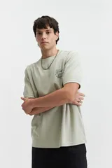 Remera de manga corta color verde claro con estampado de texto en el pecho, de corte oversize y cuello redondo.