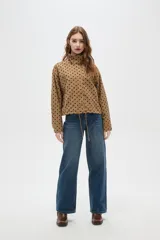 Campera color camel con estampado de lunares negros, cuello alto y cierre frontal. Tiene mangas largas y cordón ajustable en el dobladillo.