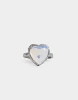 Anillo plateado con dije de piedra luna en forma de corazón.