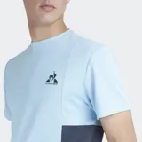 Remera deportiva Le Coq Sportif de manga corta, color celeste claro con paneles laterales en azul oscuro. Presenta cuello redondo y el logo del gallo en el pecho.