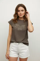 Remera negra de algodón con cuello redondo y mangas cortas. Presenta un estampado abstracto con apliques de strass dorados.