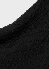 Vestido midi negro con textura, cuello barco y hombros descubiertos. Diseño entallado y manga corta. Abertura posterior en el bajo.