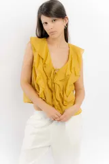 Blusa blanca de algodón con escote en V, volados en el frente y mangas cortas.