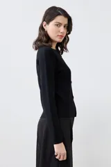 Chaqueta tejida negra con botones dorados, de corte clásico y mangas largas.