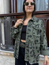 Campera de jean color beige con estampado animal print en tonos marrón y negro. Tiene cuello clásico, cierre frontal con botones, bolsillos con solapa y detalle de flecos en los bordes.