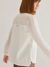 Camisa color crudo de corte recto y manga larga, con cuello mao y botones de madera. Presenta detalles de bordado calado en el frente.