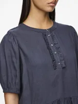 Blusa azul de mangas 3/4 con cuello redondo, botones y volantes.