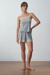 Conjunto de pijama gris compuesto por un top de breteles finos con puntilla en el escote y un short con puntilla en el ruedo.