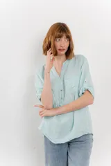 Camisa celeste de lino con cuello mao, escote en V abotonado, bolsillo en el pecho y mangas 3/4 con trabilla.