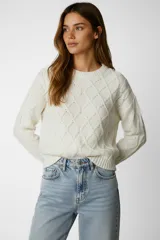 Sweater de chenille color blanco, con punto trenzado, diseño holgado y cuello a la base.