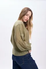 Camisa casual manga larga color verde oliva, de tela traslúcida con textura sutil. Tiene cuello redondo, cierre frontal con botones y mangas largas con puños elásticos.