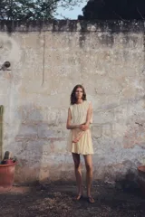 Top cropped color crema, sin mangas, de punto suave con costuras fruncidas para una silueta abullonada con efecto drapeado.