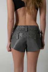 Short gris de eco cuero con doble cinturón desmontable con hebillas metálicas y tachas.