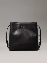 Cartera tipo saco Calvin Klein color negro, con correa ajustable para el hombro, compartimento central con cremallera, compartimento con cierre giratorio en la parte delantera, compartimento magnético en la parte trasera y herrajes plateados con el monograma de la marca.
