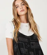 Vestido corto negro con estampado de palabras en blanco y remera blanca de manga corta con estampado de estrellas.