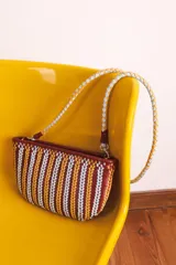 Bolso tipo bandolera, tejido en cuero color bordó, amarillo y blanco.