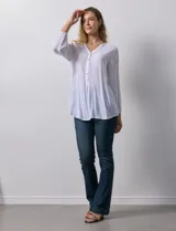 Blusa blanca de manga larga con cuello a la base y escote en V con botones. Terminación de manga con elástico.