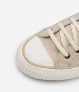 Championes bajos de lona color beige, con puntera redonda, cierre con cordones y suela de goma blanca con detalle de línea en relieve.