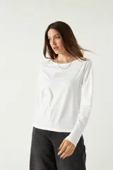 Remera de manga larga color blanco con cuello redondo amplio y estampado en el frente.