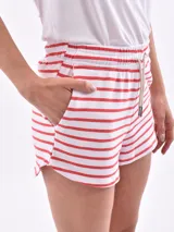Short blanco con rayas horizontales rojas, cintura elastizada con cordón ajustable y bolsillos laterales.