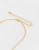 Cadena corta dorada con dije de moño plateado y corazón dorado.