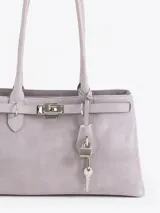 Bolso de mano tipo satchel color marrón oscuro, confeccionado en cuero descarne (gamuza). Presenta dos asas superiores y un cierre frontal con broche metálico dorado. Incluye un candado y una llave colgante como detalle.