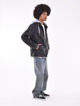 Campera negra de cuero sintético con capucha de algodón gris desmontable y cierre frontal con cremallera.
