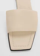 Sandalias bajas color beige con punta cuadrada, destalonadas y con abertura en la parte delantera.