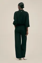 Pantalón negro de crepe con corte recto, cintura elastizada, bolsillos laterales y terminaciones en cobre.