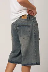 Bermuda de jean azul con efecto lavado y roturas en la parte delantera.