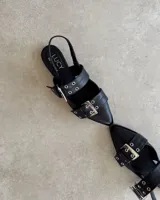 Chatas de cuero vacuno color negro, con punta fina, tira sobre el empeine con hebilla metálica y tira trasera con elástico.