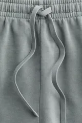 Short gris de felpa de algodón con efecto lavado, corte holgado, cintura elástica con cordón ajustable, bolsillos laterales y traseros, y aberturas laterales en el ruedo.