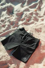 Bermuda negra de corte recto con cordón ajustable en la cintura y logo bordado en blanco en la pierna izquierda.