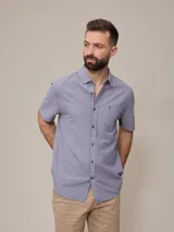 Camisa de manga corta con rayas verticales azules y blancas, confeccionada en algodón.
