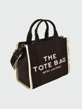 Bolso tote de tela color beige con estampado del logo de la marca en negro. Tiene doble asa de mano y correa de hombro extraíble y ajustable en color negro.