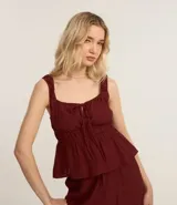 Blusa texturizada color borgoña, con breteles anchos, escote cuadrado, lazo en el busto y volado en el ruedo.
