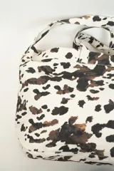 Bolso tipo tote bag con estampado de cebra en tonos beige y blanco. Tiene doble asa corta y correa larga para colgar del hombro.