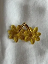 Aros colgantes plateados con dije de flor acrílica color dorado.