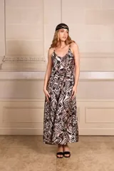 Vestido largo tipo solera, con breteles finos y escote cuadrado. Presenta un estampado batik/floral en tonos negro y beige/rosado pálido.