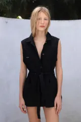 Chaleco negro de jean con cuello camisero, sin mangas, con cierre frontal abotonado y bolsillos delanteros.