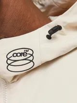 Campera shell ligera color beige, de manga larga con capucha y fit cómodo. Confeccionada en tejido plano fino de nylon, con cierre frontal de cremallera, bolsillos delanteros funcionales y puños de canalé.